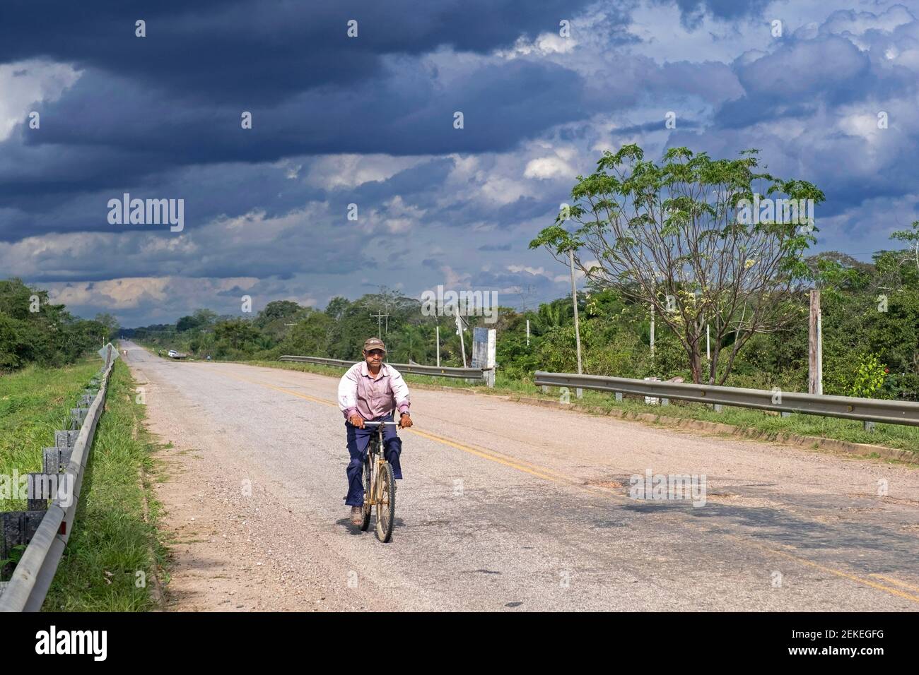 Anziano boliviano uomo in bicicletta lungo la strada Ruta Nacional 9 / RN 9 in Amazzonia, Provincia di Marbán, Dipartimento Beni, Bolivia Foto Stock