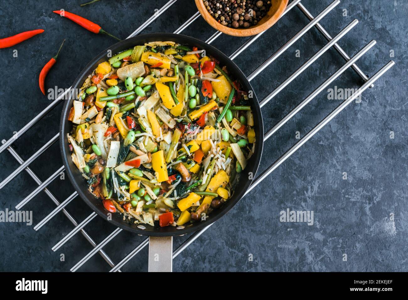 Verdure asiatiche fresche mescolano, wok thailandese in una padella nera  sullo sfondo nero con spazio di copia. Cibo sano Foto stock - Alamy