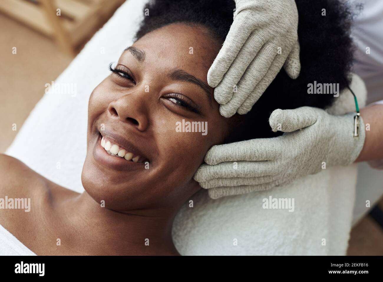 Massaggio viso con guanti con microcorrenti. Terapia microcorrente.  Cosmelotologist fa massaggio facciale stimolante con guanti elettrici.  Giovane hopp Foto stock - Alamy
