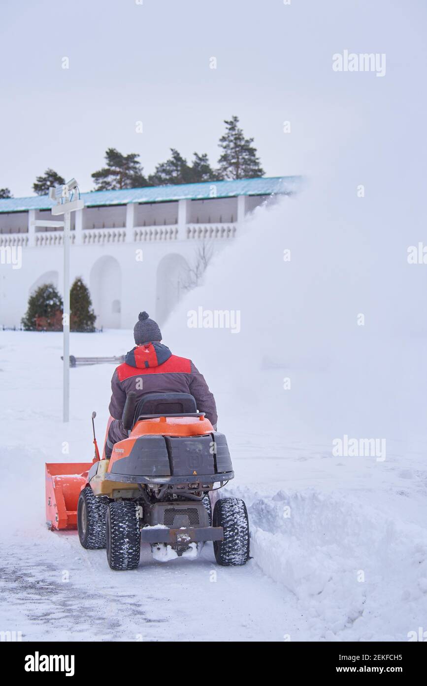 Russia, regione di Mosca, febbraio 2021. UN uomo vestito di calore su un aratro di neve rimuove la neve sul territorio del monastero in una giornata gelida. Foto Stock