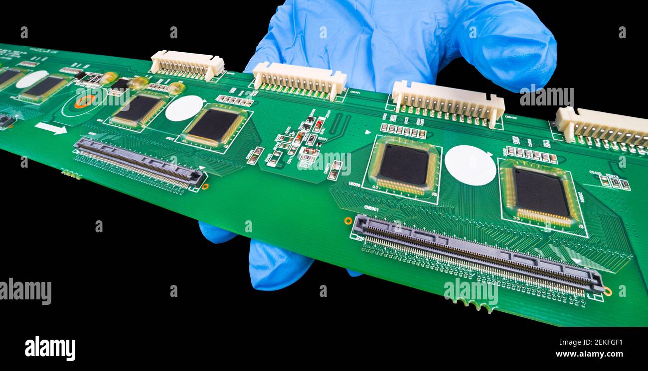 Lunga scheda elettronica a circuito stampato a portata di mano in guanto blu. Tecnologia a montaggio superficiale su circuito stampato verde. Connettori bianchi. Schegge in gel protettivo. Foto Stock