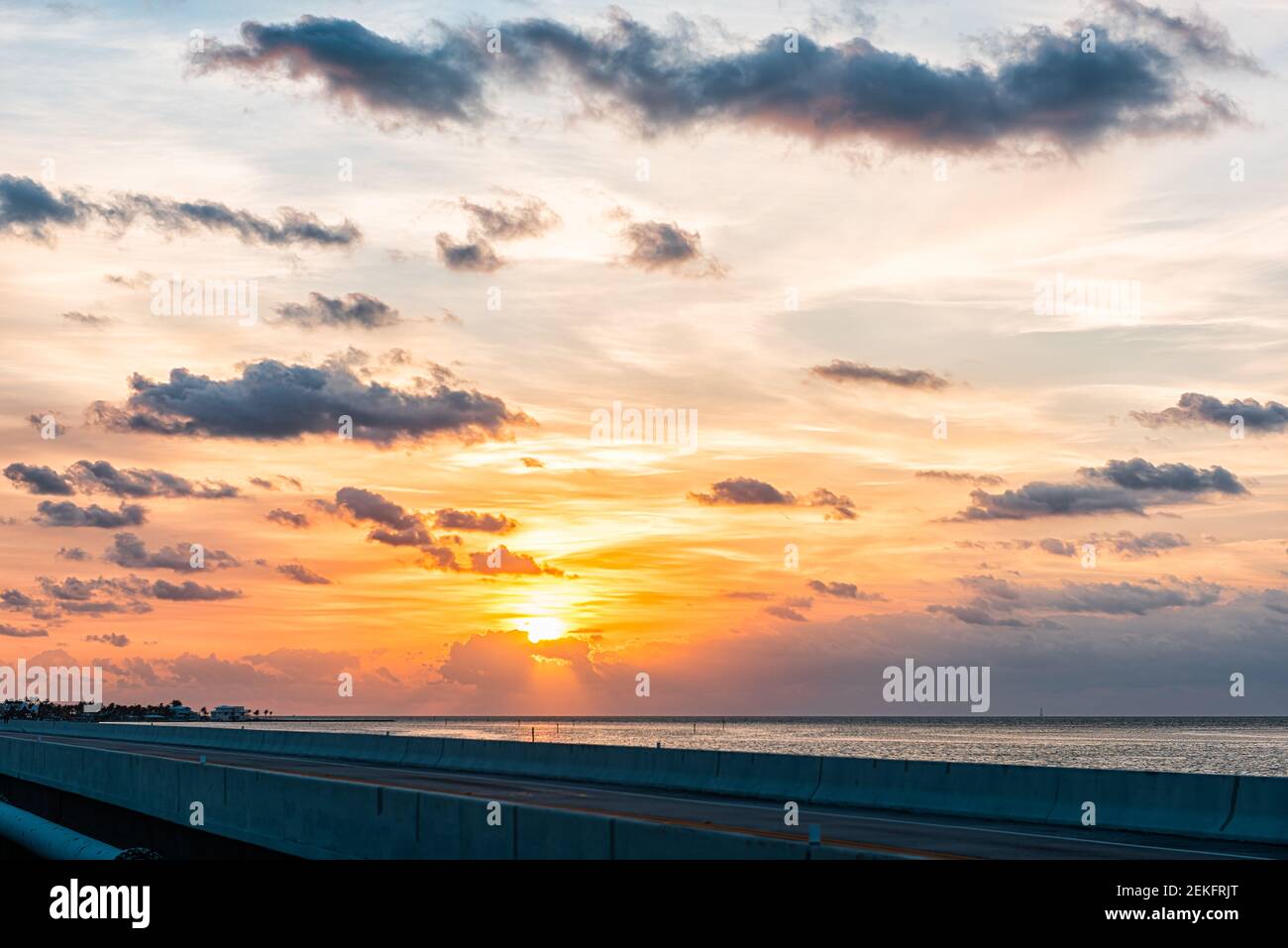 Alba a Islamorada, Florida chiavi con il cielo arancione colorato da oltreoceano strada ponte sul Golfo del Messico con le nuvole nel cielo nuvoloso Foto Stock