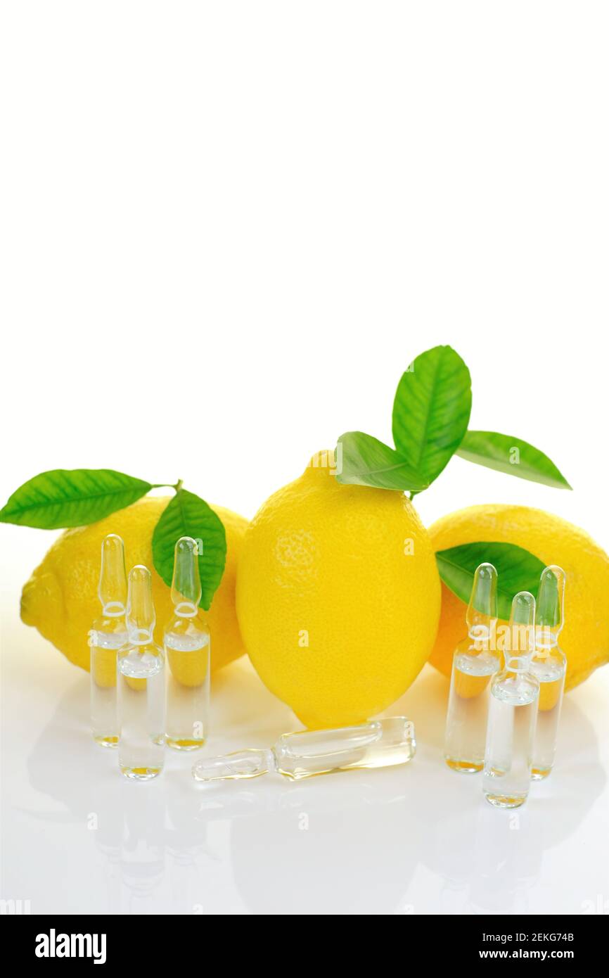 Vitamina C.Serum con set fiale trasparenti di vitamina C., limoni frutta con foglie verdi su sfondo bianco con reflection.Beauty e salute Foto Stock