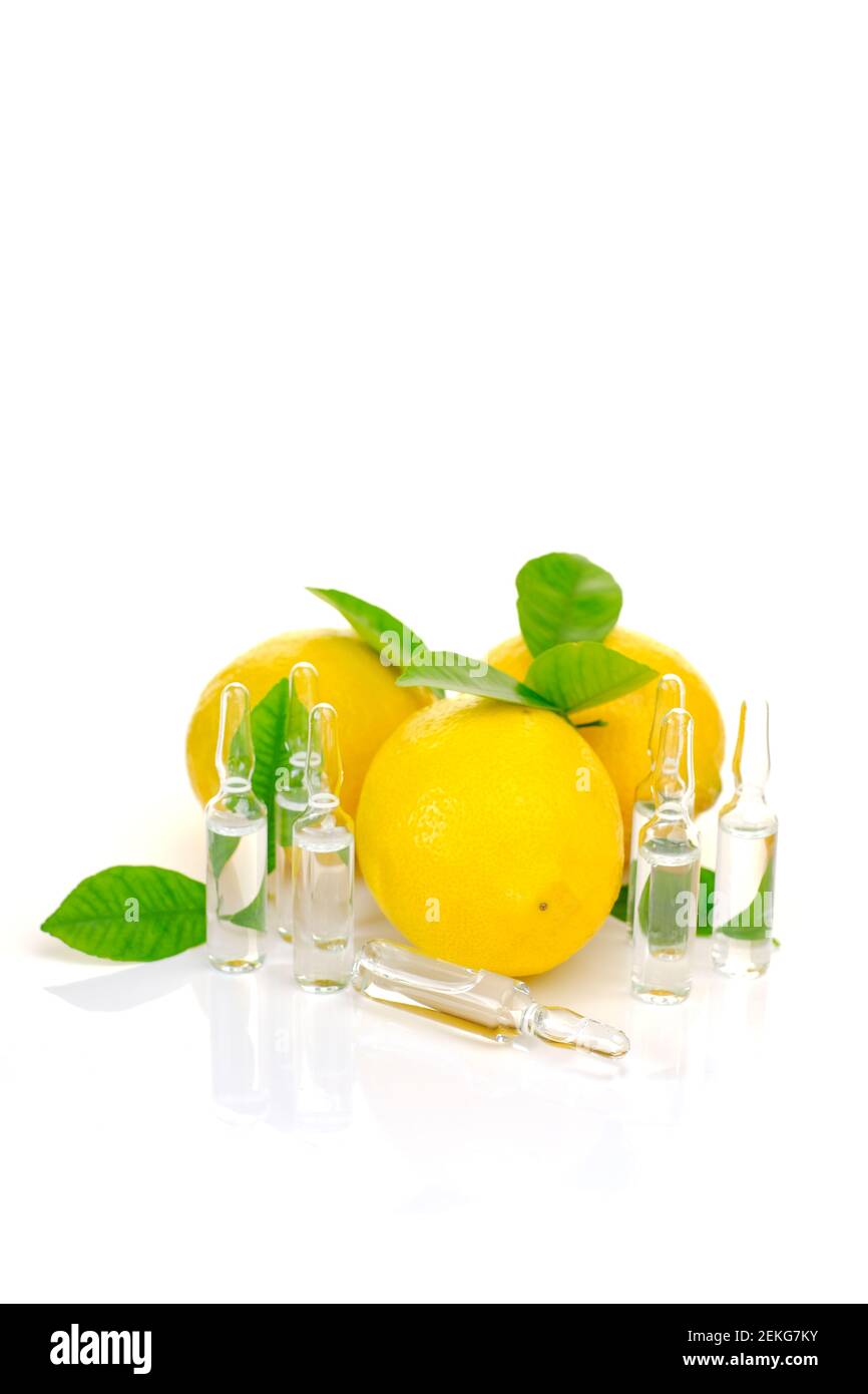 Vitamina C. prevenzione dell'immunità da virus.siero con vitamina C. ampolle set, limoni frutti con foglie verdi su sfondo bianco con Foto Stock
