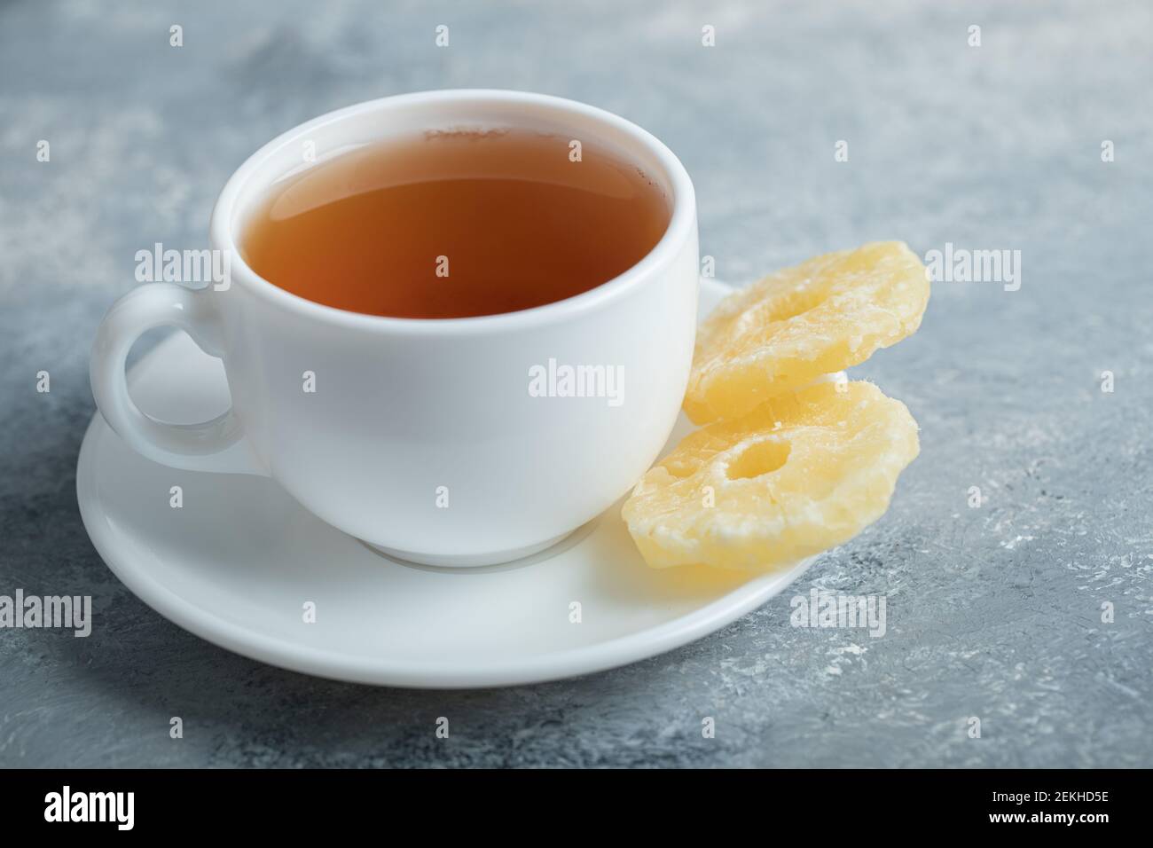 Una tazza di tè aromatico con ananas essiccato su a. sfondo scuro Foto Stock