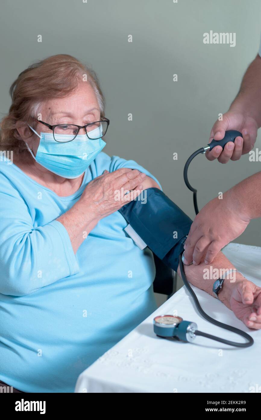 Viene mostrato come prendono la pressione sanguigna ad un Donna latina anziana Foto Stock