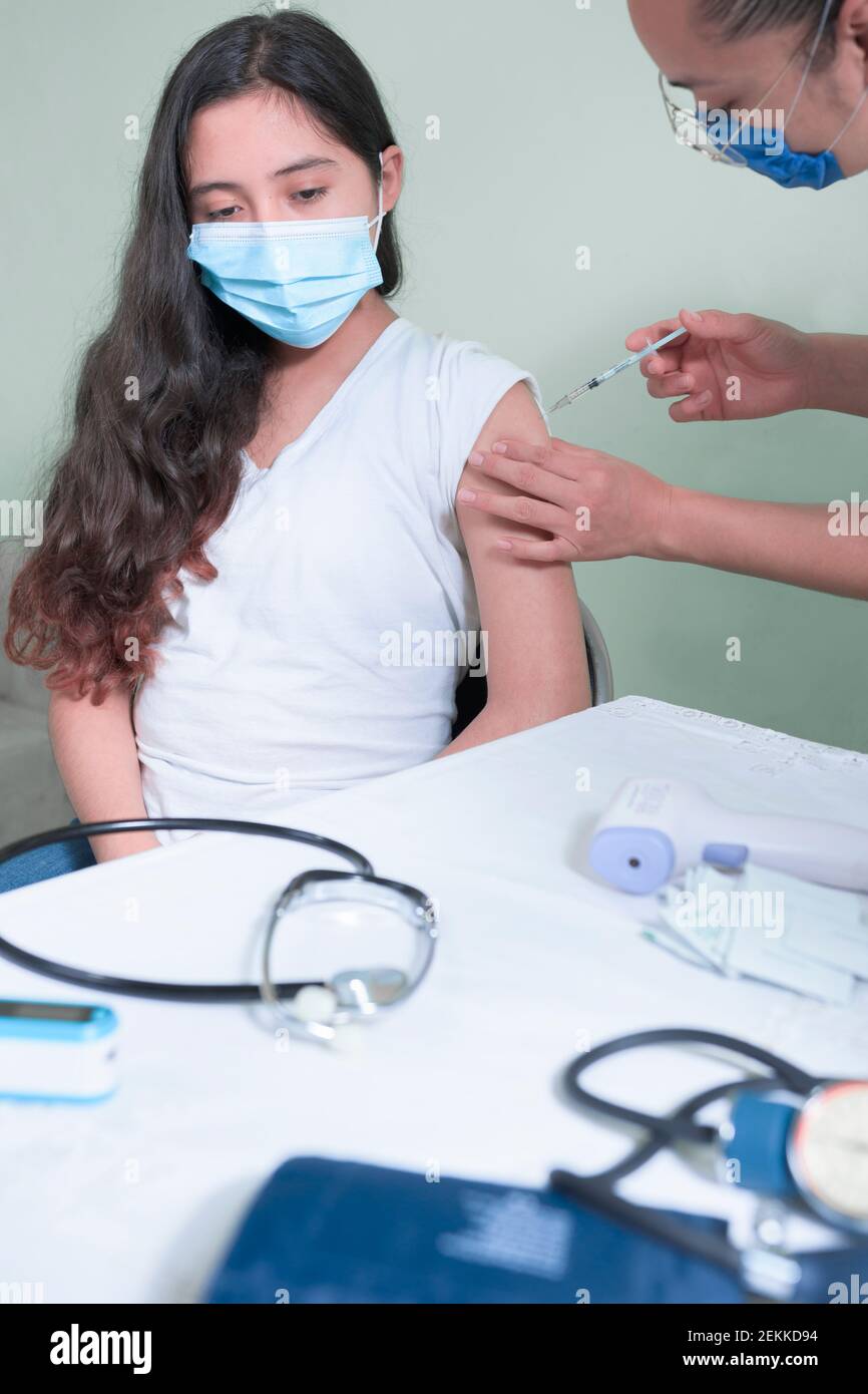 iniezione di vaccino ad adolescenti in pandemia Foto Stock