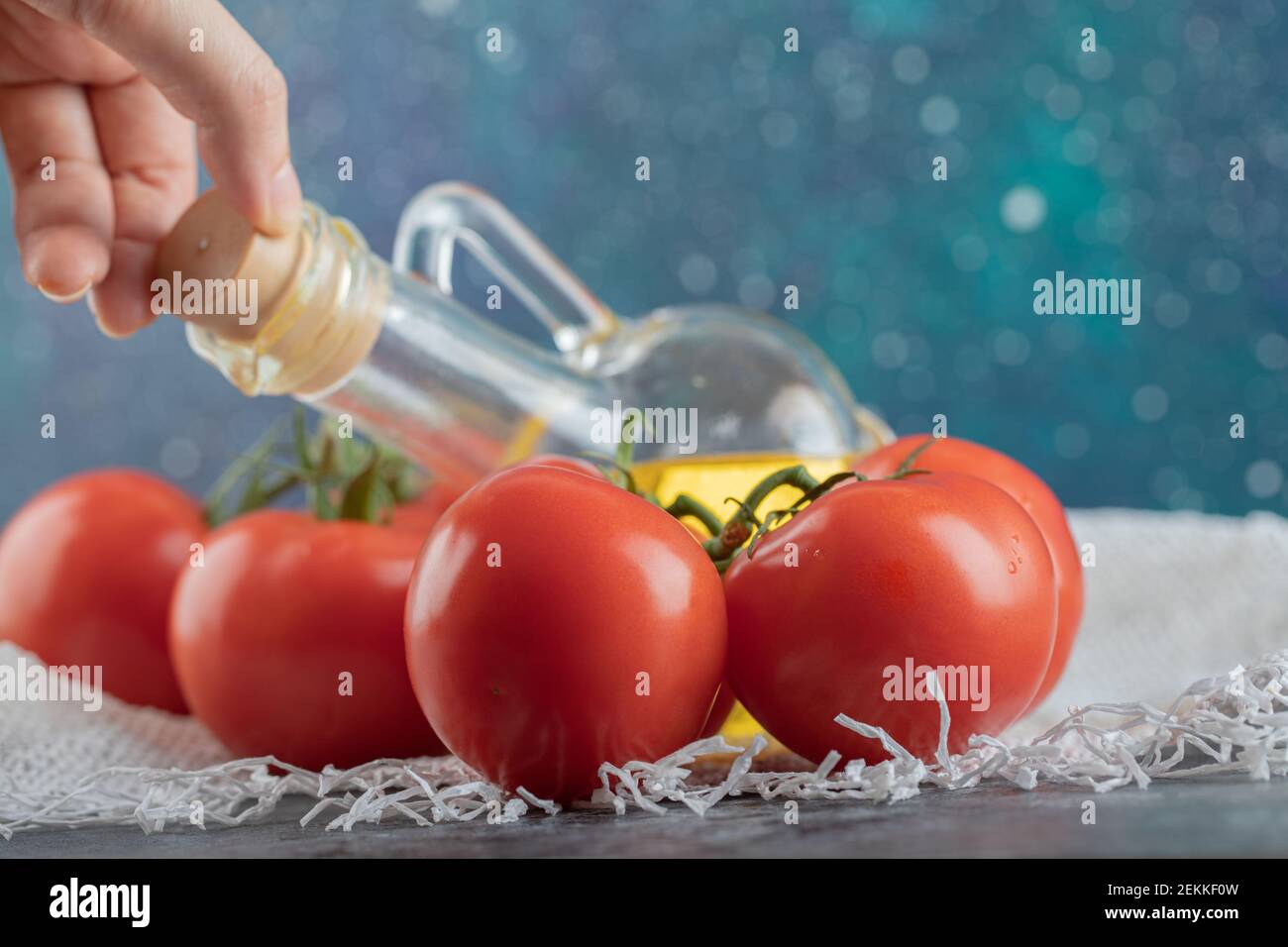 Mano prendendo una bottiglia di vetro di olio su un colorato sfondo Foto Stock