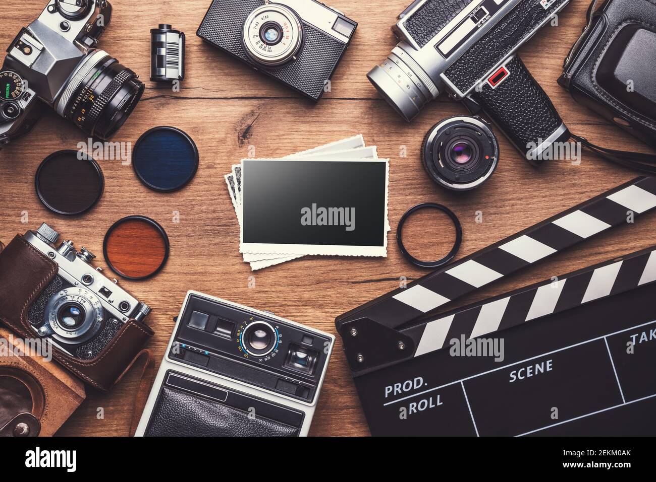 Fotocamera retrò d'epoca con clapboard e vecchie foto su sfondo di legno, tracciato di ritaglio Foto Stock