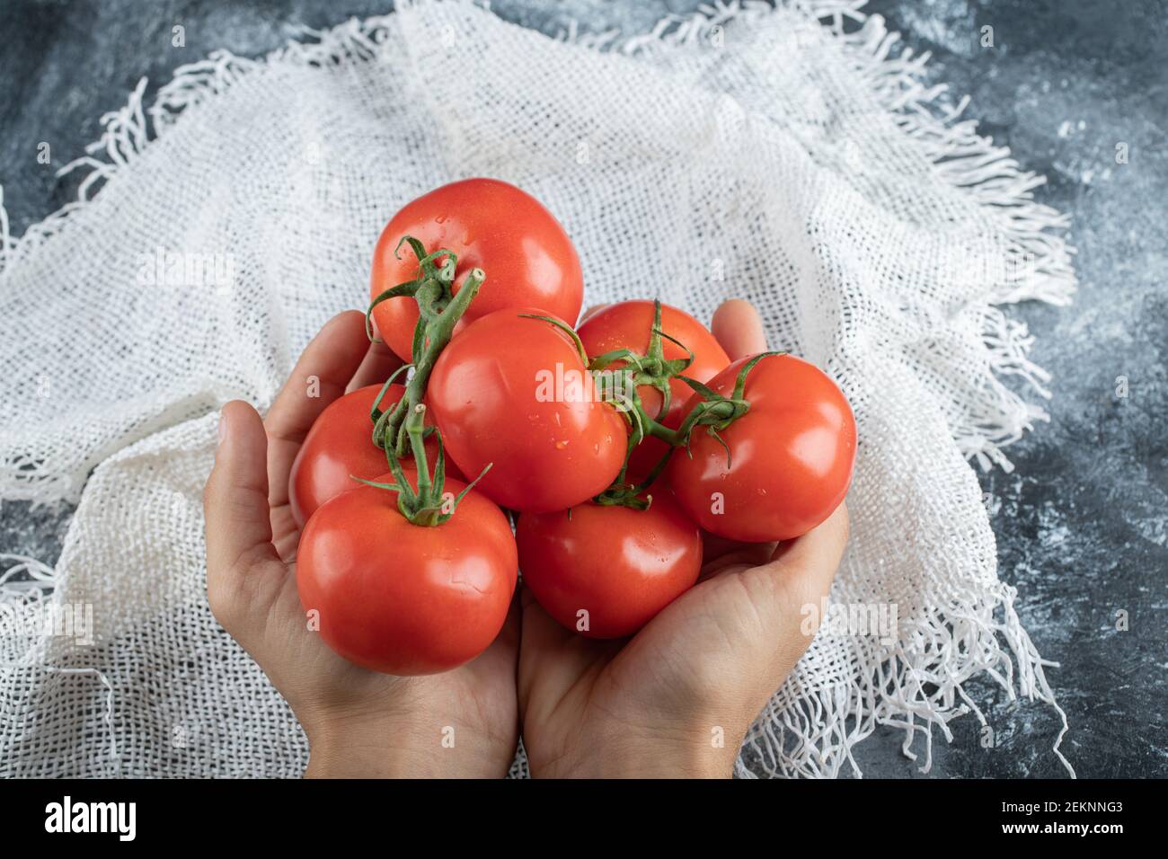 Mani dell'uomo che tengono un mazzo di pomodoro su un colorato sfondo Foto Stock