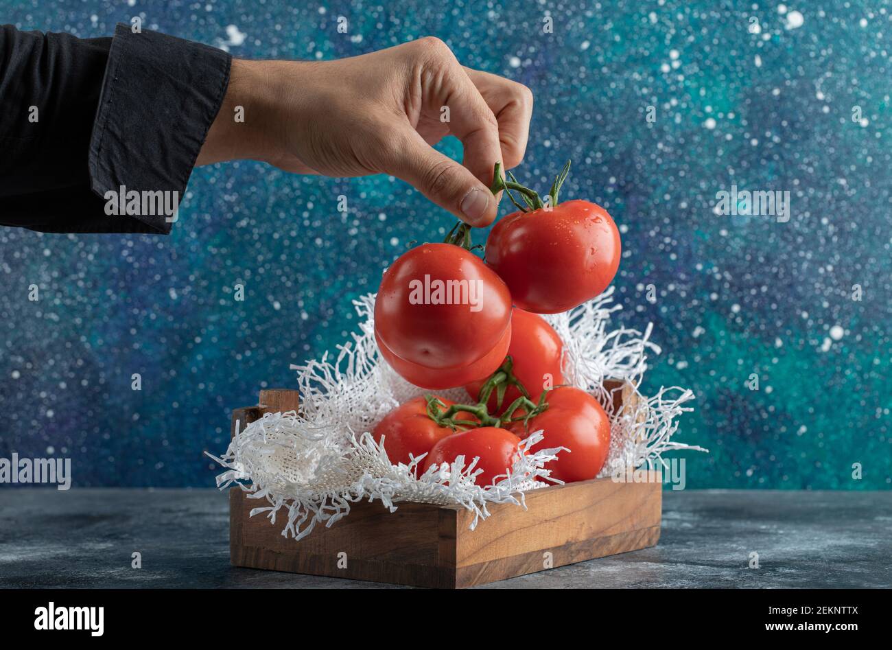 Mano dell'uomo che tiene un mazzo di pomodoro su un colorato sfondo Foto Stock