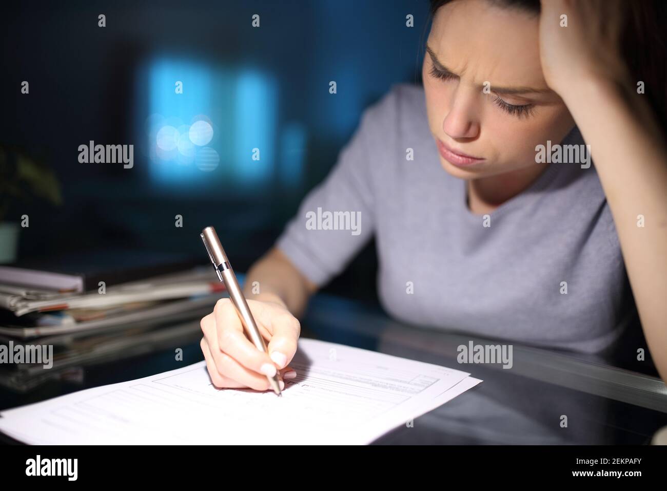 Donna preoccupata che riempiono il modulo di carta nella notte a casa Foto Stock