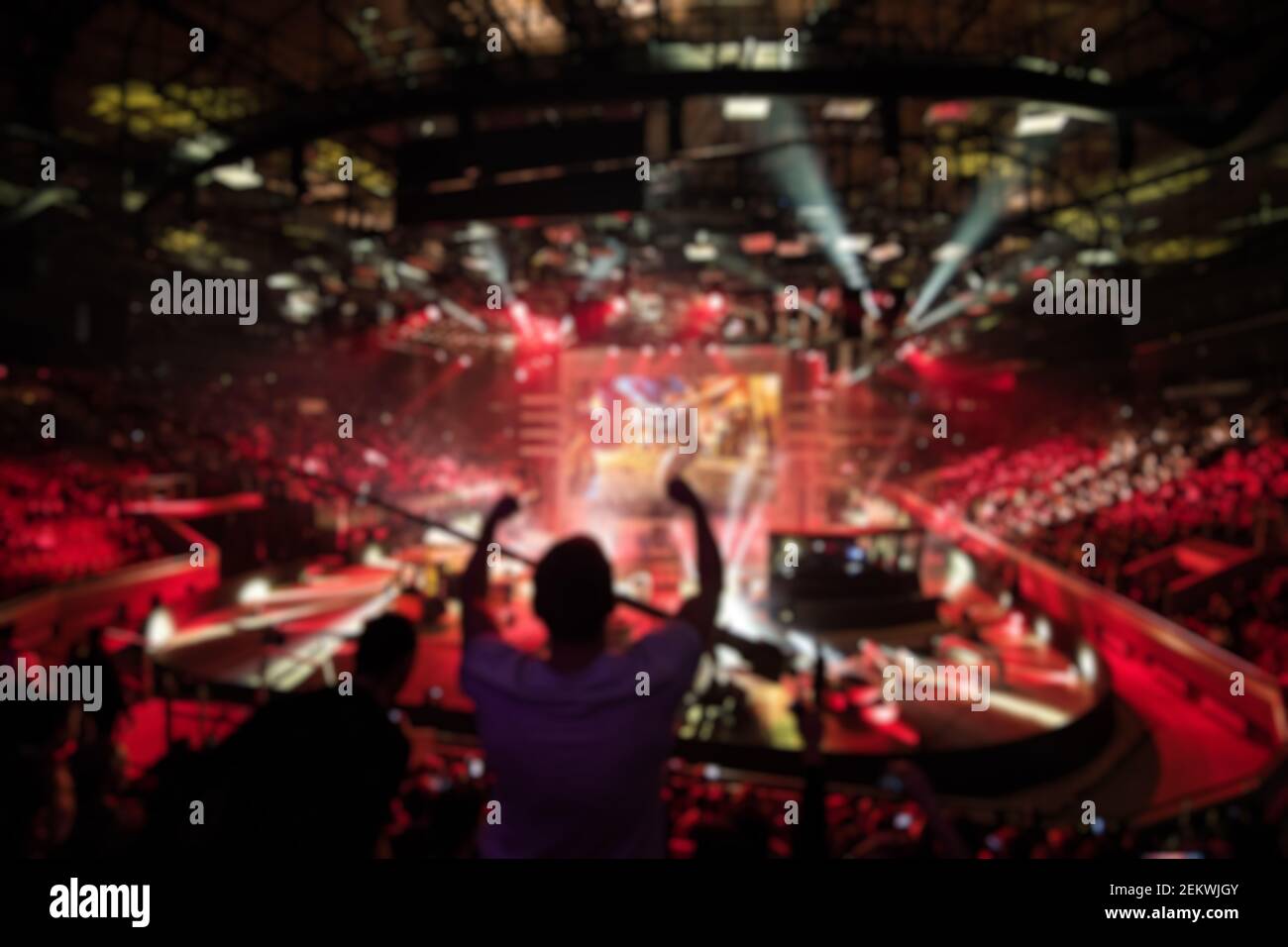 Astratto sfondo offuscato di grandi eventi di gioco eSport alla grande arena. Uomo con le mani sollevate. Foto Stock