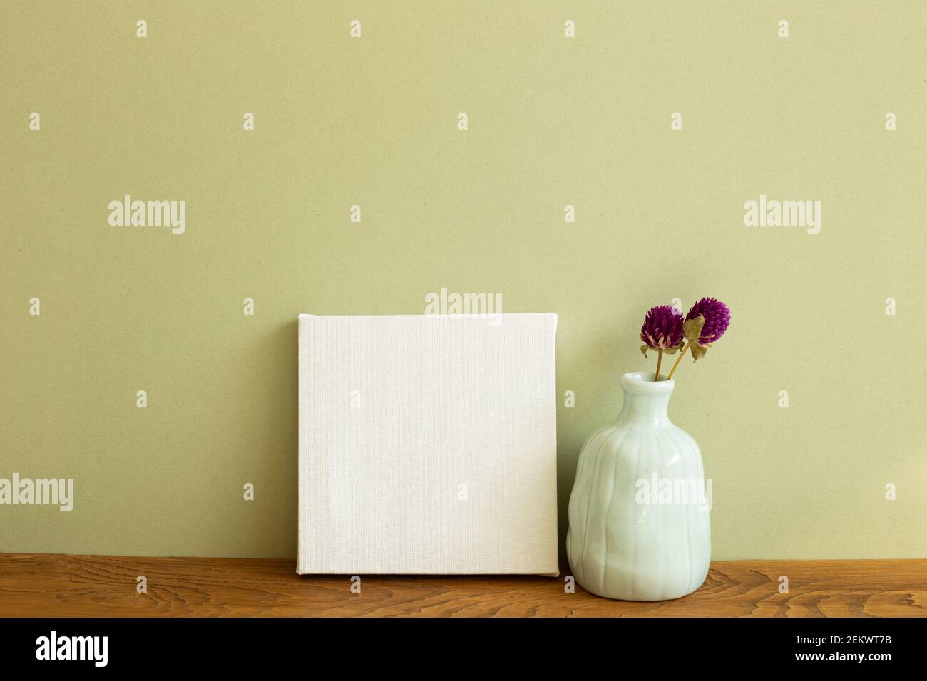 Tela bianca e vaso di fiori secchi su tavolo di legno. Sfondo verde kaki. Spazio copia Foto Stock