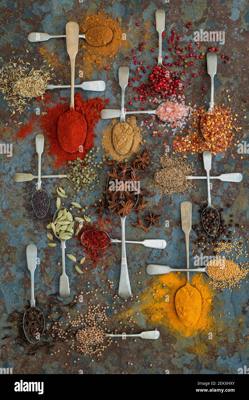 Spezie aromatiche su cucchiai su fondo di ardesia Foto Stock