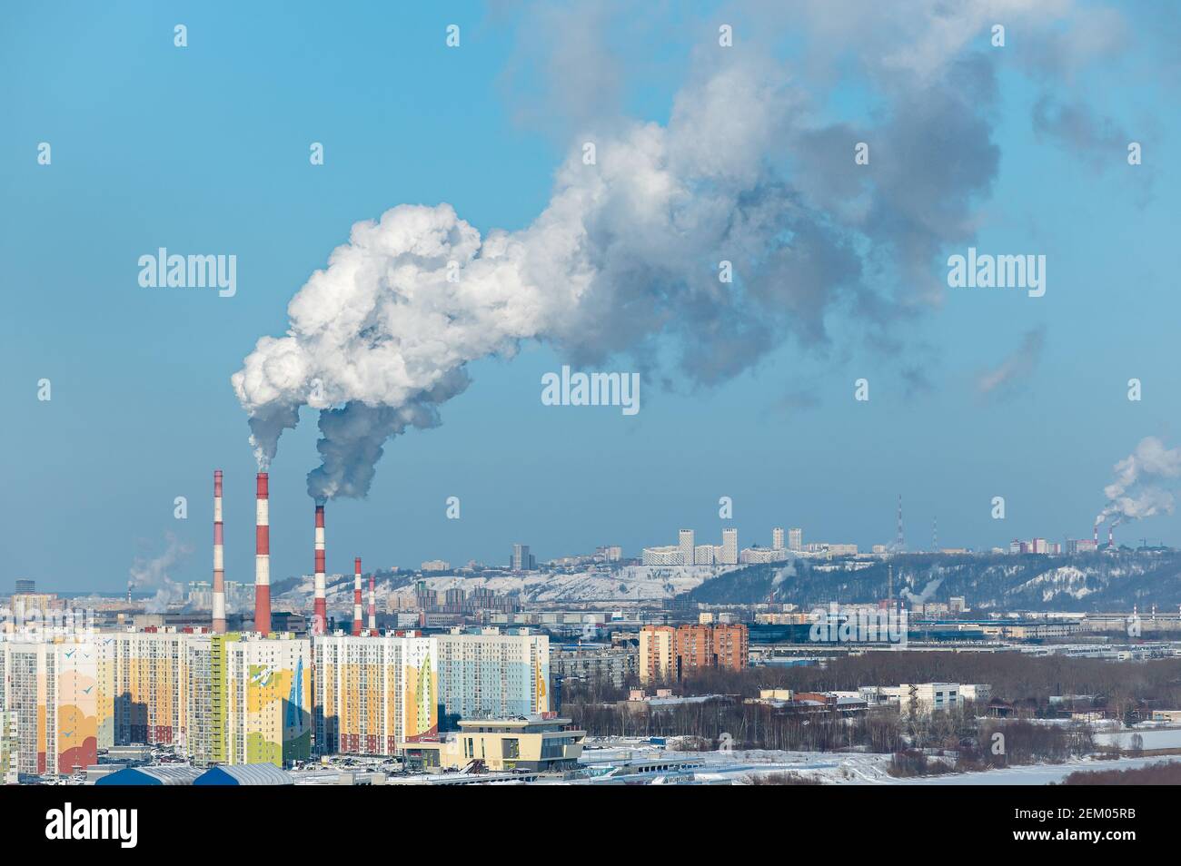 Fumo da camini di centrale a carbone. Edifici residenziali in primo piano. Edificio residenziale sullo sfondo dei camini fumanti Foto Stock