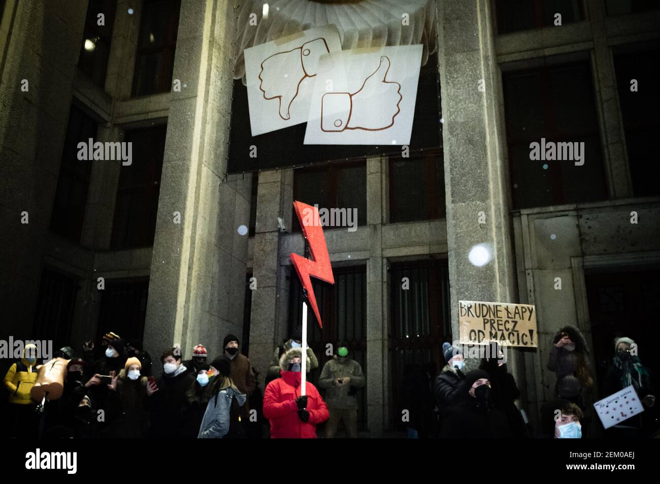 Un protester in è visto tenendo una luce rossa, il simbolo dello Sciopero delle donne durante la dimostrazione. I simboli dei social media come e come sono visibili Foto Stock