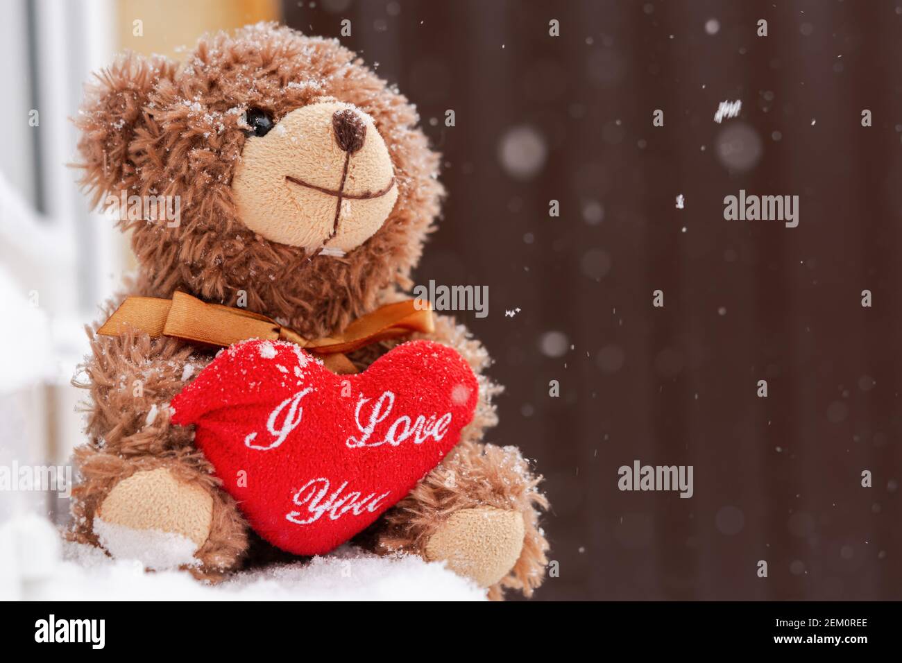 Un orsacchiotto con un cuore sulla finestra. Il concetto di una vacanza di San Valentino, teneri sentimenti romantici, una dichiarazione d'amore. Sfondo sfocato Foto Stock
