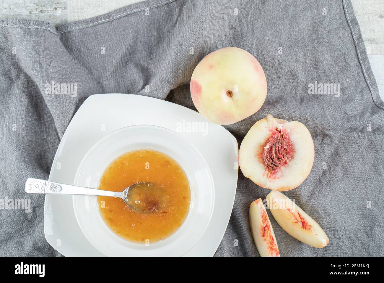 Un piatto bianco pieno di confettura di pesche e cucchiaio Foto Stock