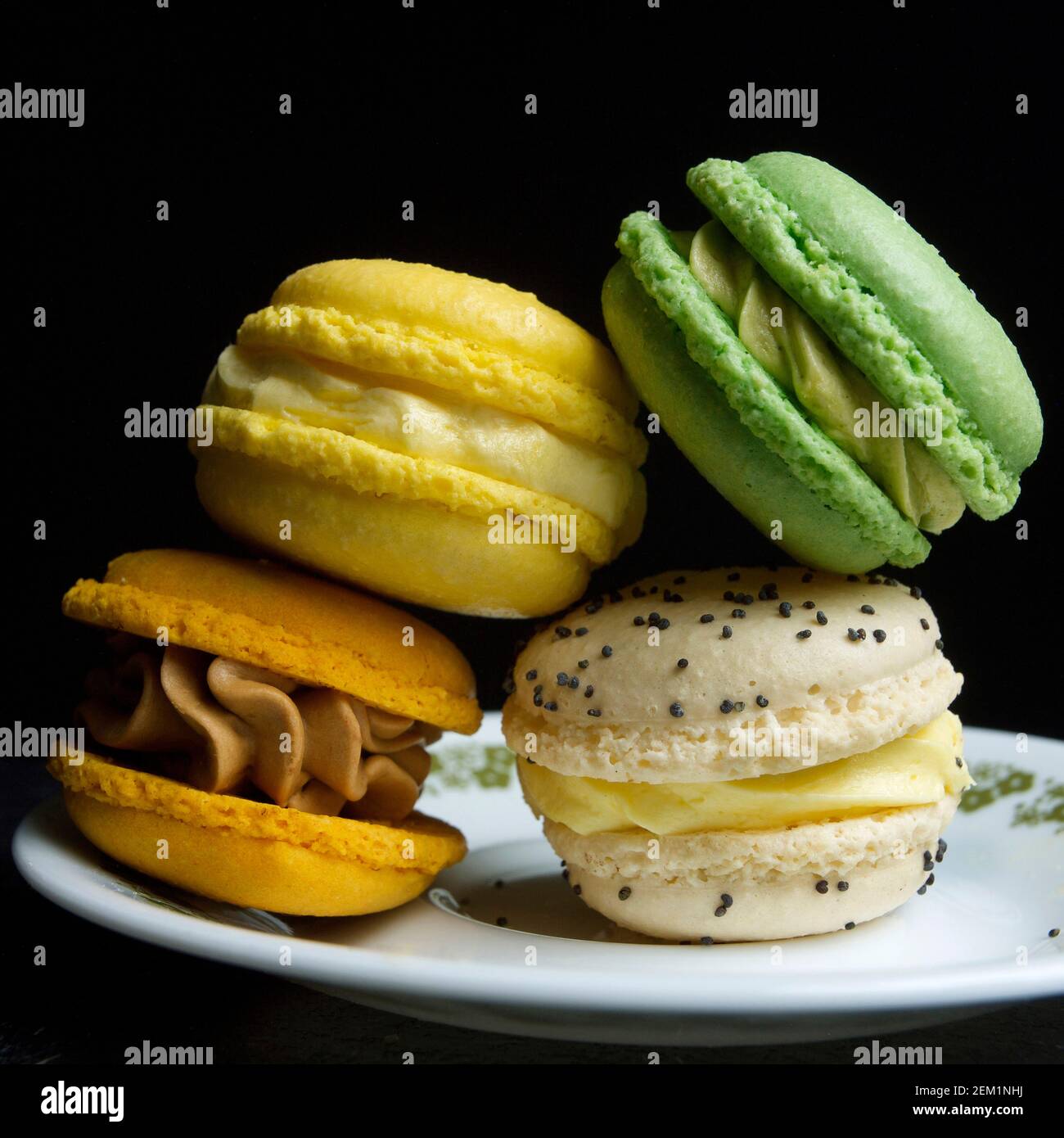 Macaron colorati impilati elegantemente su un piatto su uno sfondo scuro che mostra disegni intricati e colori vivaci Foto Stock