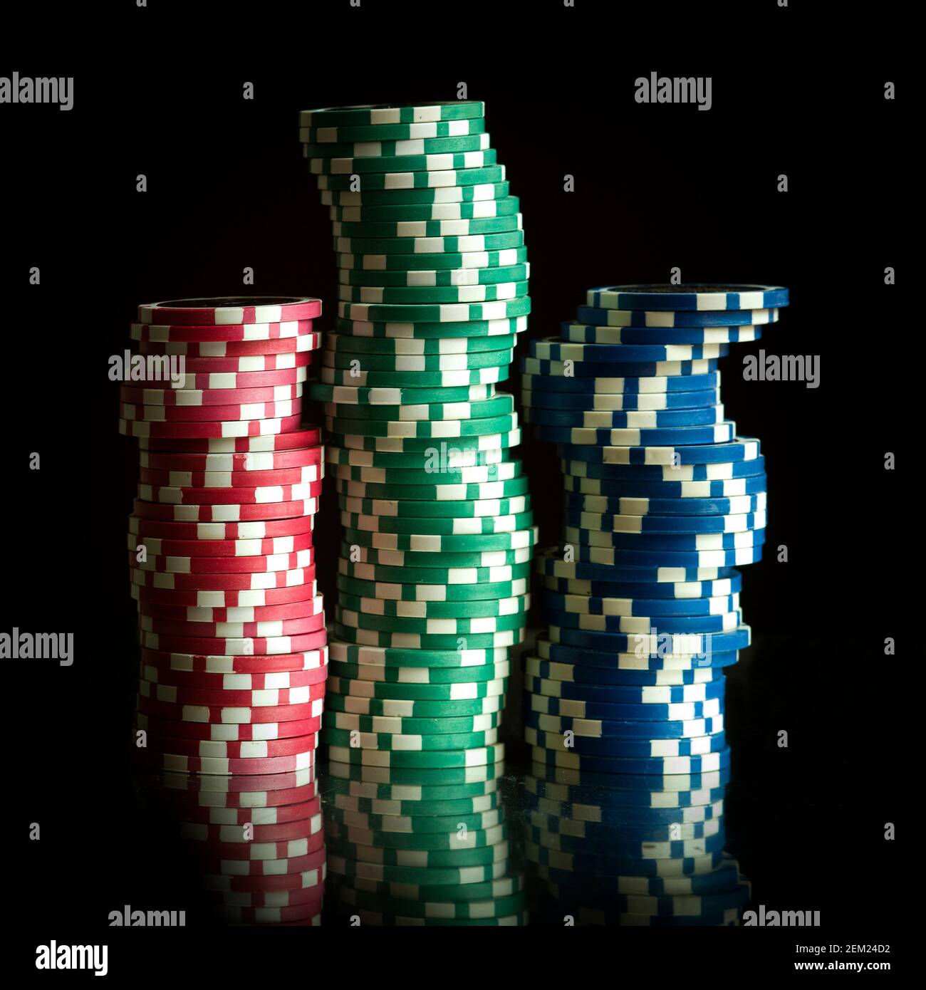 Pile di chip colorate da poker con un dado rosso su sfondo scuro, perfette per gli appassionati di giochi e per i giochi d'azzardo Foto Stock