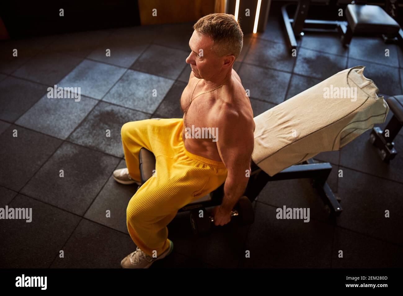 Atleta concentrato usando panca e manubri per esercitarsi Foto Stock