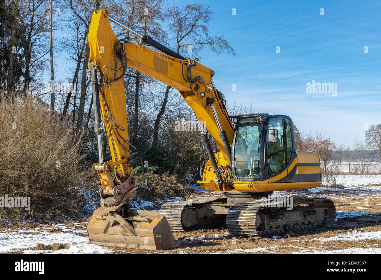 Grande escavatore parcheggiato su un prato in inverno Foto Stock