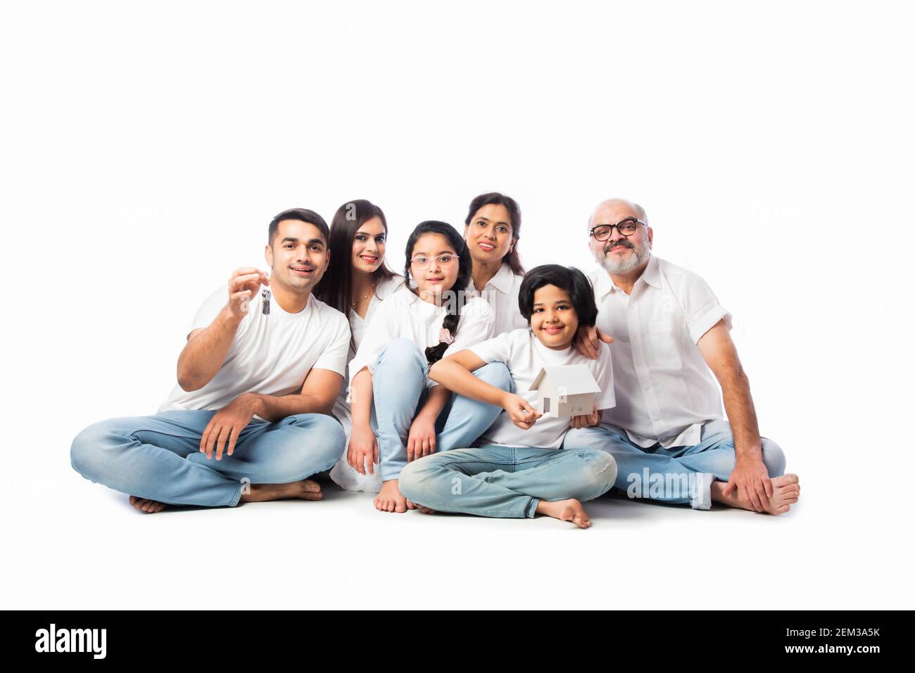 Famiglia indiana e concetto immobiliare - multigenerazionale famiglia asiatica tenere modello di casa di carta con tasti su sfondo bianco Foto Stock