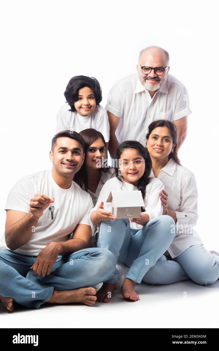 Famiglia indiana e concetto immobiliare - multigenerazionale famiglia asiatica tenere modello di casa di carta con tasti su sfondo bianco Foto Stock