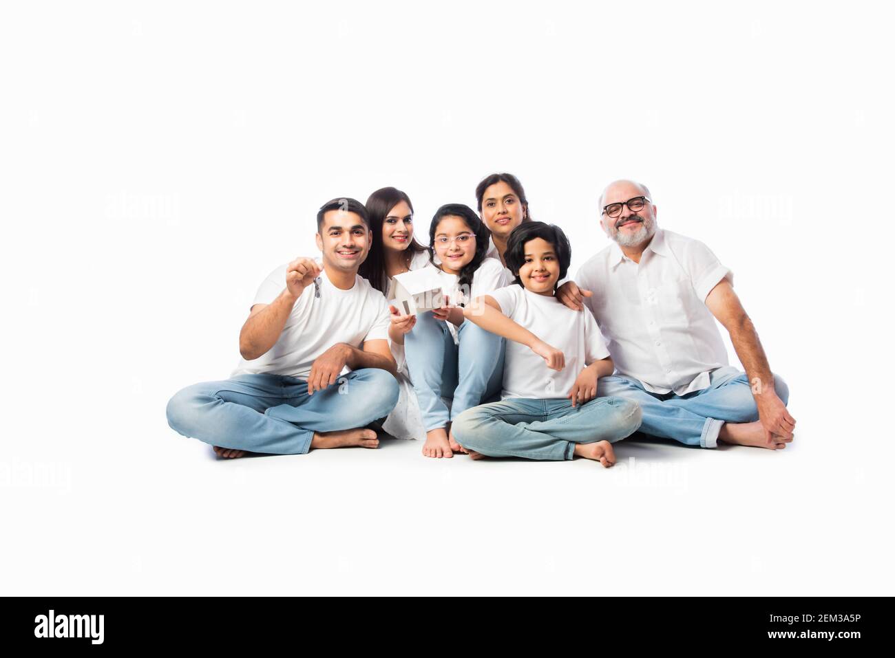 Famiglia indiana e concetto immobiliare - multigenerazionale famiglia asiatica tenere modello di casa di carta con tasti su sfondo bianco Foto Stock