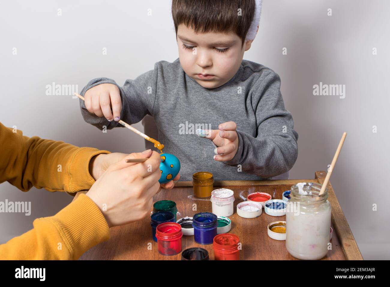 Madre e figlio dipingono insieme le uova di pollo per la vacanza di Pasqua. Preparandosi per Pasqua. Tradizioni familiari. Foto Stock