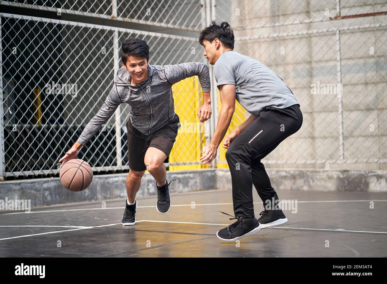 due giovani uomini adulti asiatici che giocano a basket uno a uno sul campo all'aperto Foto Stock