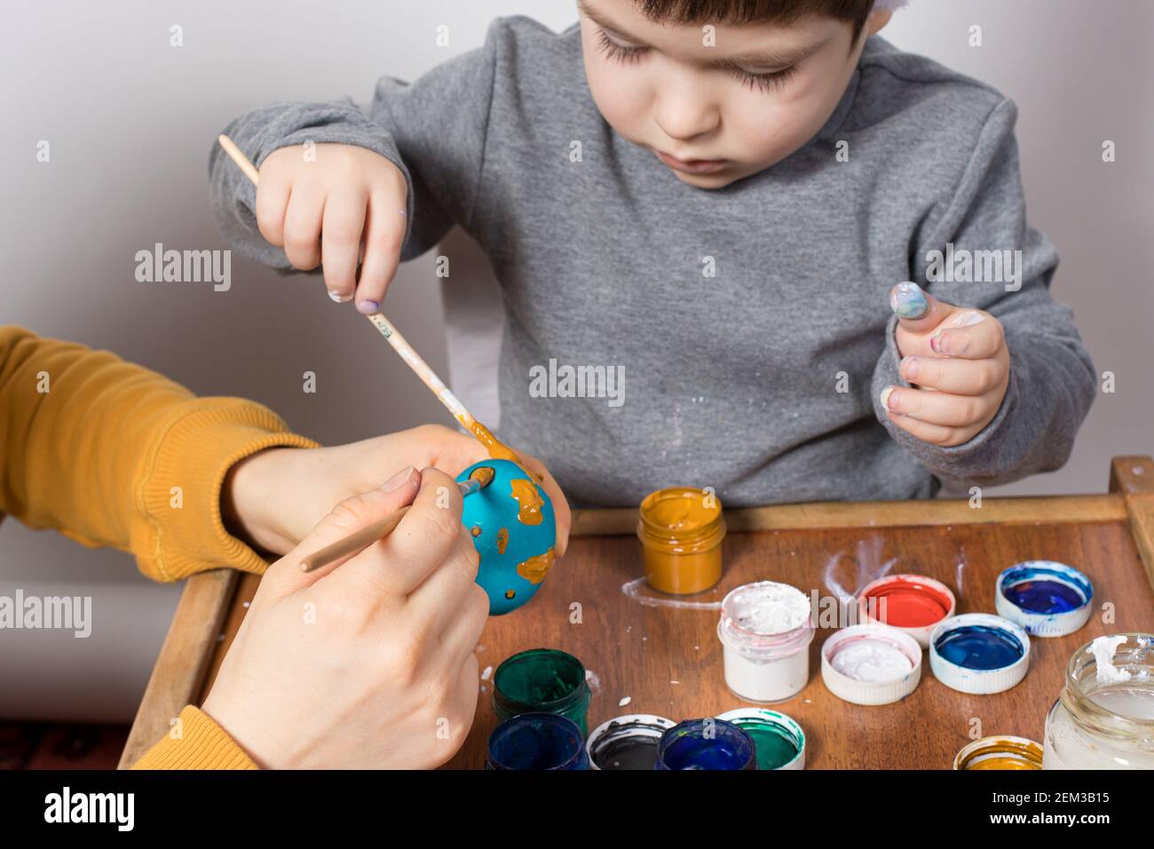 Madre e figlio dipingono insieme le uova di pollo per la vacanza di Pasqua. Preparandosi per Pasqua. Tradizioni familiari. Foto Stock