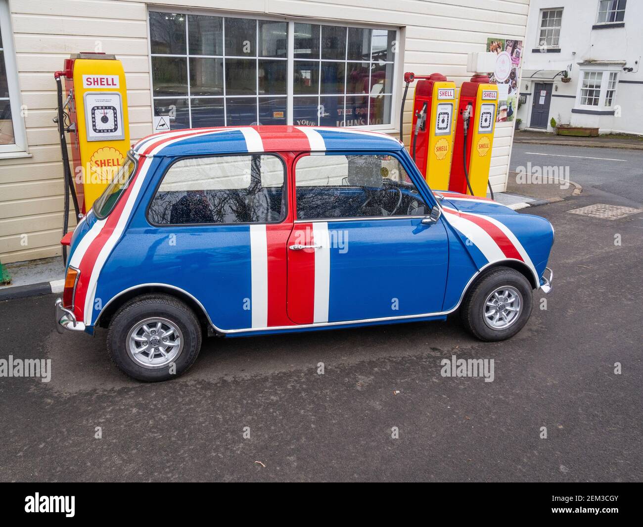 Vintage Austin Mini in Union Jack colori davanti alle vecchie pompe a benzina Shell, Patishall, Northamptonshire, UK Foto Stock