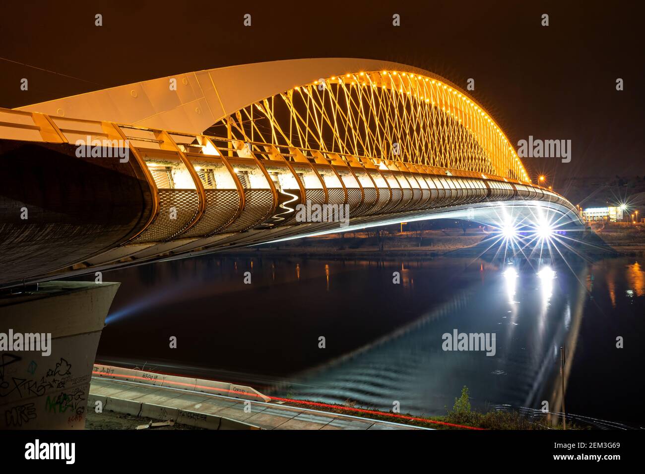 Ponte luminoso e moderno che attraversa un fiume di notte. Moderna architettura cittadina. Costruzione per il traffico Foto Stock