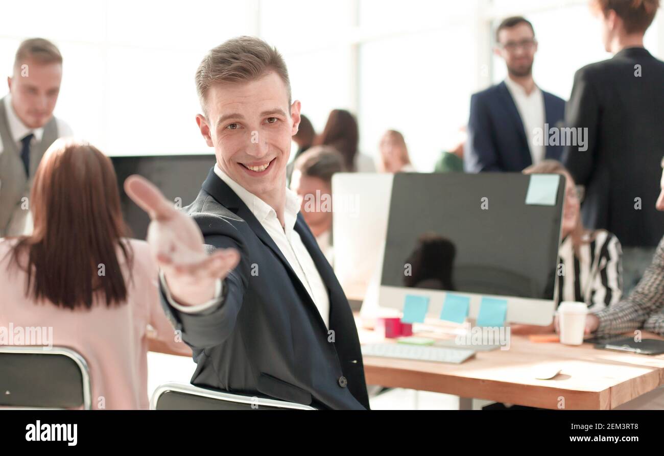 Giovane uomo d'affari cordiale seduto alla sua scrivania Foto Stock