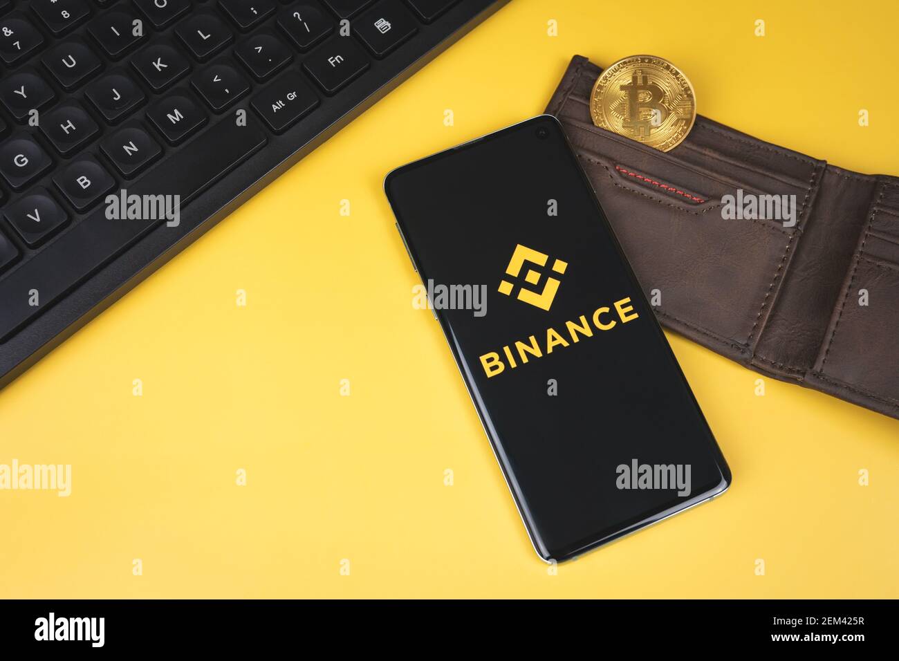 Logo dell'app mobile Binance su uno smartphone, portafoglio con Bitcoin oro  e tastiera su sfondo giallo Foto stock - Alamy