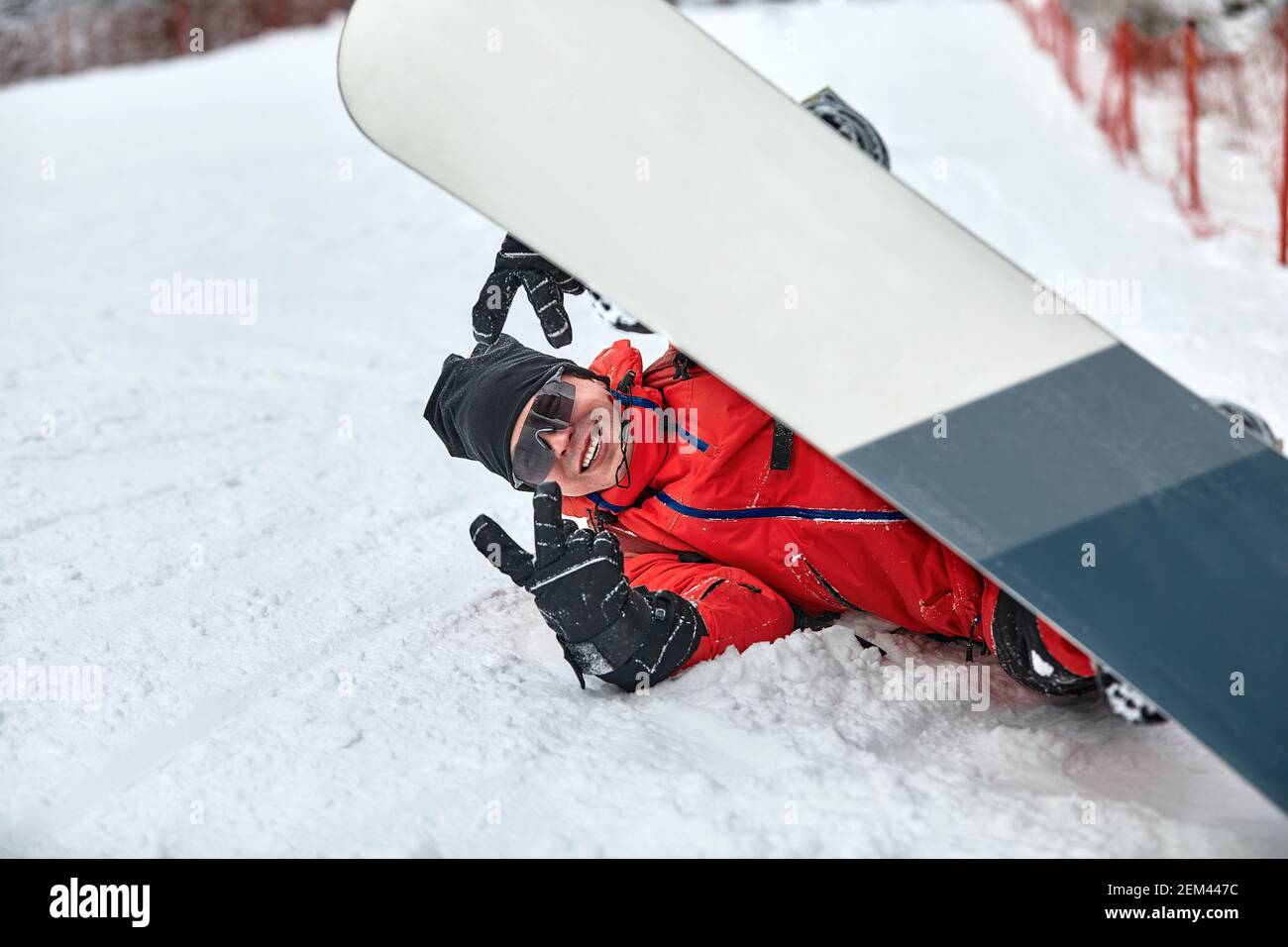 L'uomo in tuta da sci rossa si siede sulla collina con lo snowboard Foto  stock - Alamy