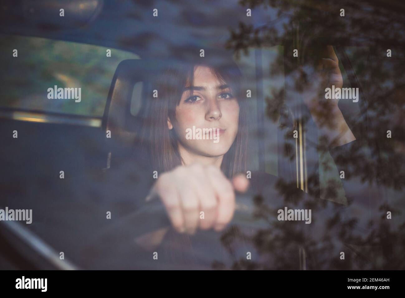 Foto della giovane bruna adolescente sul sedile del conducente. Vista attraverso il parabrezza Foto Stock