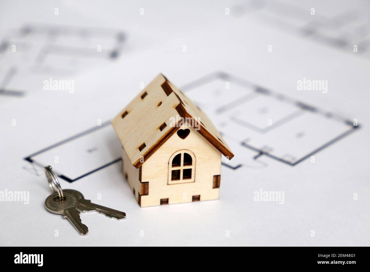 Modello di casa in legno e chiavi sullo sfondo della pianta dell'appartamento. Disegno di casa, acquisto di beni immobili Foto Stock