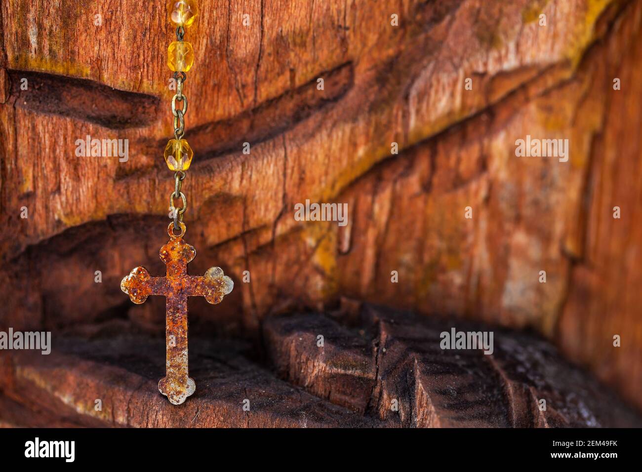 Una croce di alluminio poco costosa appesa su una statua di legno della Vergine Maria. Luce naturale, oggetto all'ombra Foto Stock