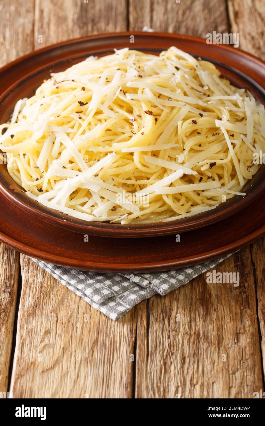 Spaghetti Cacio e Pepe Ricetta primo piano nel piatto sul tavolo. Verticale Foto Stock