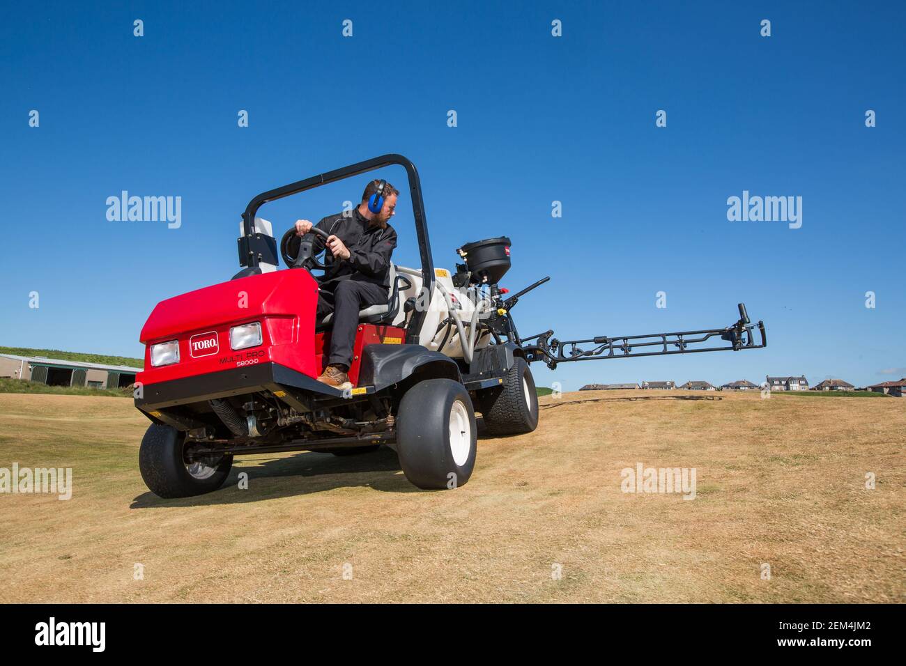 Un greenkeeper che usa un moderno spruzzatore sul campo da golf Foto Stock