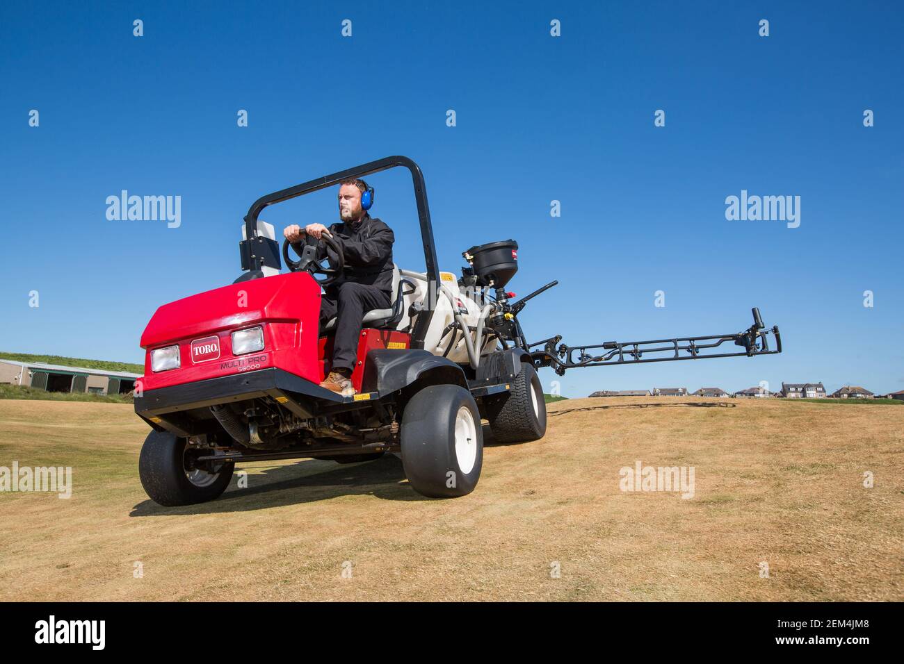 Un greenkeeper che usa un moderno spruzzatore sul campo da golf Foto Stock