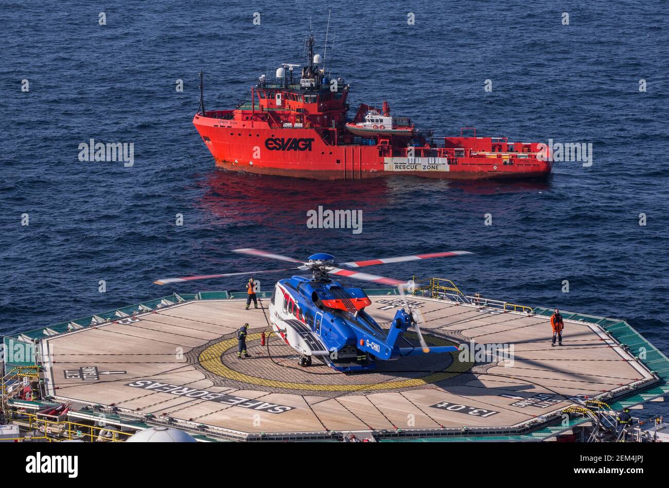 Un elicottero Sikorsky S-92 sull'eliporto su un impianto offshore di petrolio e gas nel Mare del Nord. È possibile vedere anche un'imbarcazione in standby Foto Stock