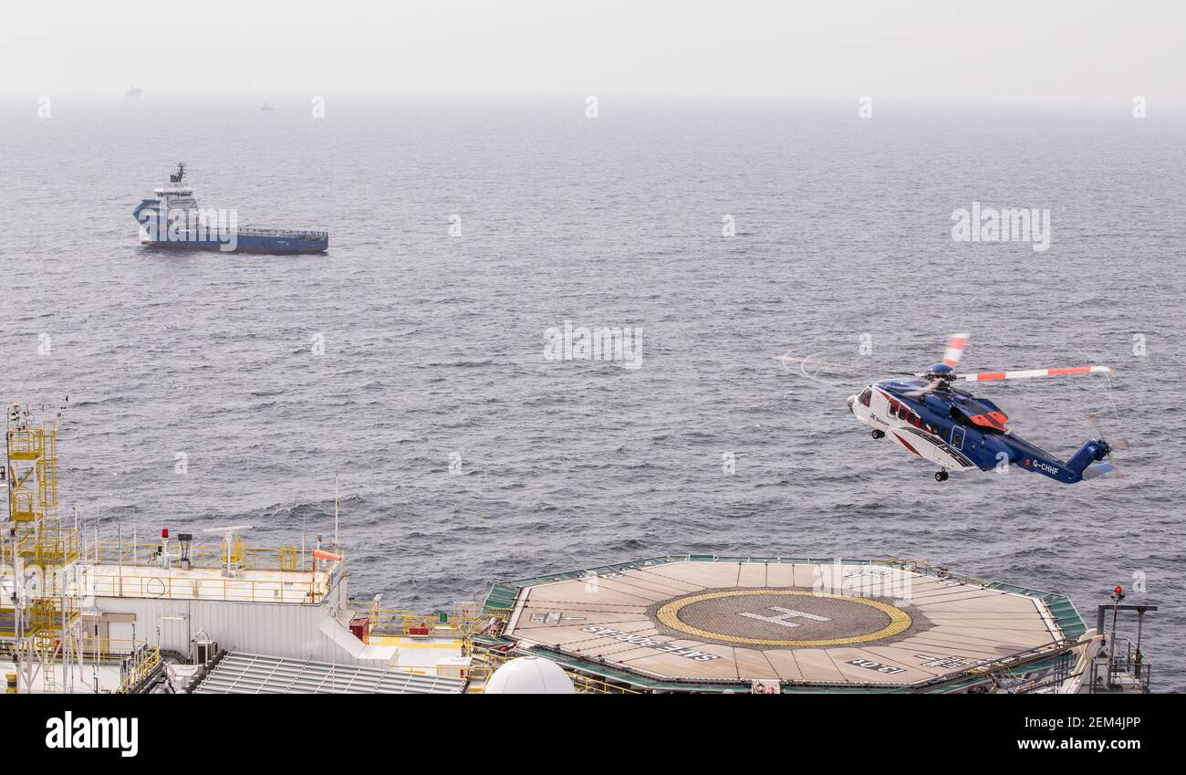 Un elicottero Sikorsky S-92 arriva a terra sull'eliporto su un impianto offshore di petrolio e gas nel Mare del Nord. È visibile un serbatoio di alimentazione Foto Stock