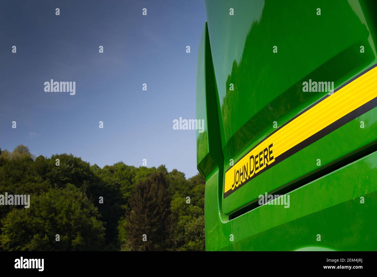 Simbolo John Deere sulla macchina agricola sotto il sole con il blu cielo e alberi Foto Stock