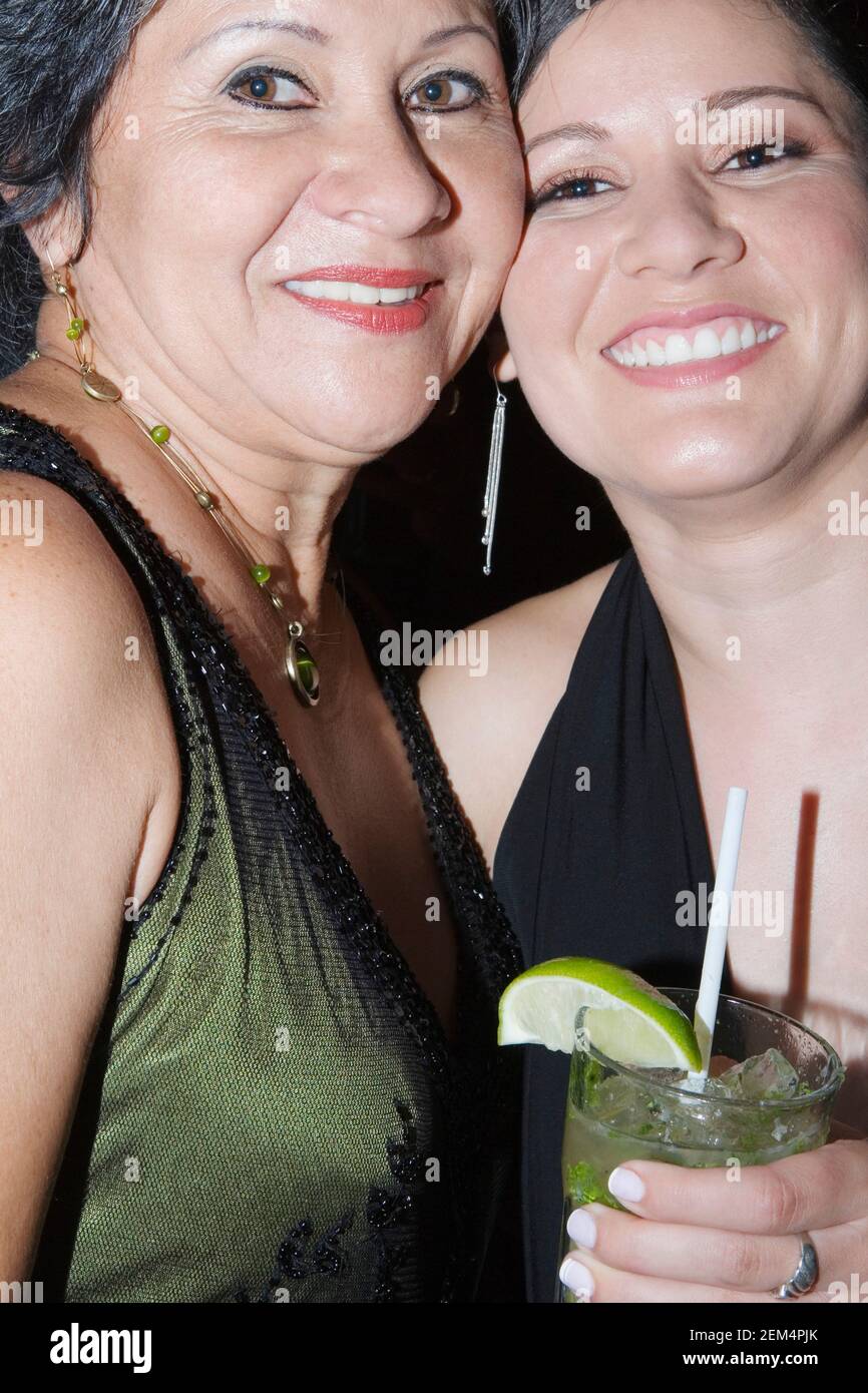 Primo piano di una giovane donna che sorride e tiene un bicchiere piena di limonata con sua madre Foto Stock