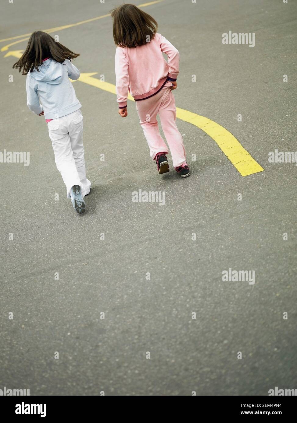 Vista posteriore di due ragazze che camminano sulla strada Foto Stock