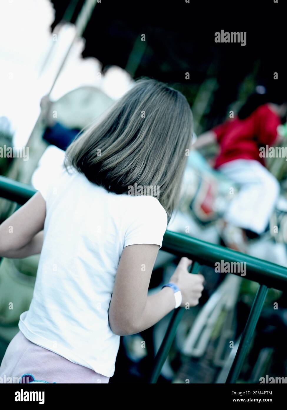 Vista posteriore di una ragazza in piedi vicino a una giostra Foto Stock